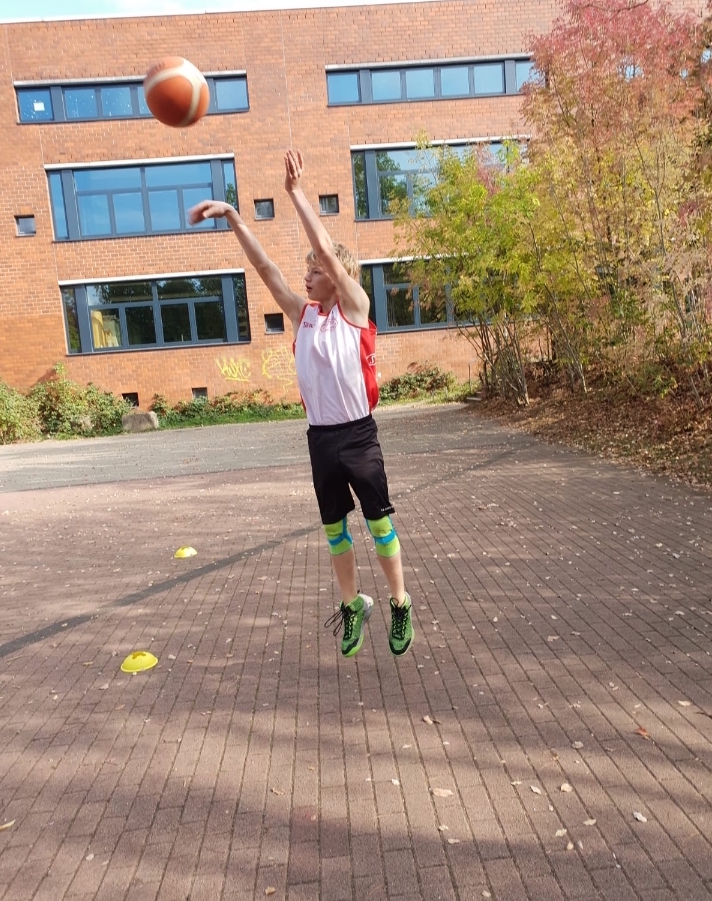 Ein Junge wirft auf einen Basketballkorb.
